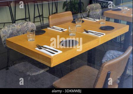 Looking through a restaurant window to an empty table and chair set for lunch, UK Stock Photo