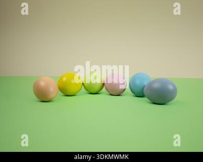 Pastel-colored eggs lined up on a green surface with a plain background for decoration Stock Photo
