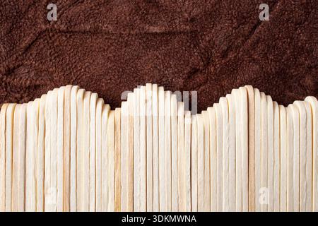 Many wooden sticks arranged like a wave fence on brown leather background, abstract textures Stock Photo