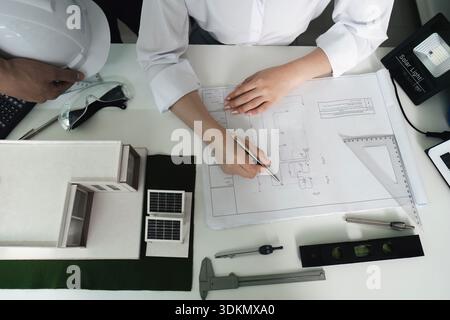 A man and a woman are working on a drawing of a building Stock Photo