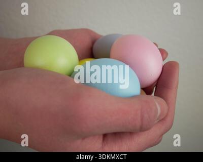 Easter holiday background. Hands cradle pastel-colored eggs in a neutral setting with a soft focus Stock Photo