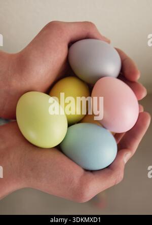 Easter holiday background. Hands grasp five colorful eggs in pastel shades, showcasing Easter theme Stock Photo