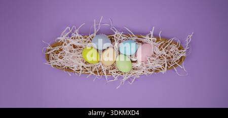 Easter holiday background. Colorful eggs are arranged in a wooden basket with shredded paper underneath Stock Photo