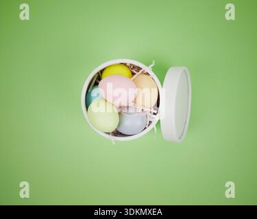 Easter holiday background. Colorful eggs are placed in a white round box on a green surface Stock Photo