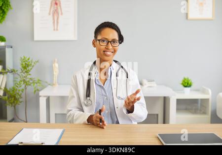 Smiling female doctor with stethoscope consulting patient in bright modern clinic Stock Photo