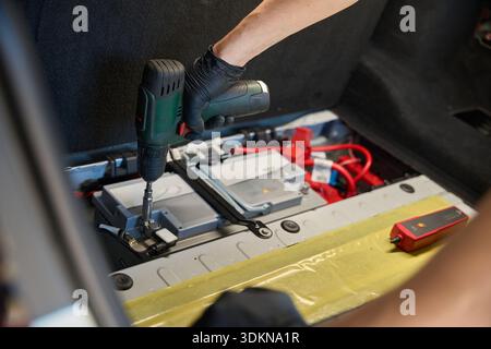 Worker secures a part in the trunk with a tool Stock Photo