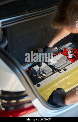 Mechanic uses a drill for work in the trunk Stock Photo