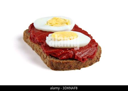 Toast of wholemeal rye bread spread with tomato paste and boiled chicken eggs isolated on white background. Stock Photo