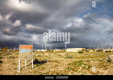 Joshua Tree National Park Sign is on the ground in a desert. The sky is cloudy and the sun is not visible Stock Photo