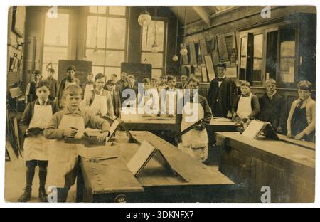 Original 1920's era postcard of boys in wood working class, dated from collars. Master in background. Saws, hammers, set square, unknown location, School children. School classroom. UK Stock Photo