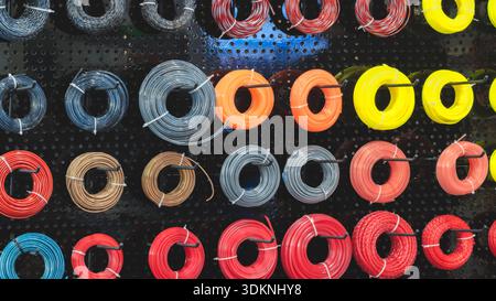 Spools of various trimmer lines hang in row on display case of specialty store. Stock Photo