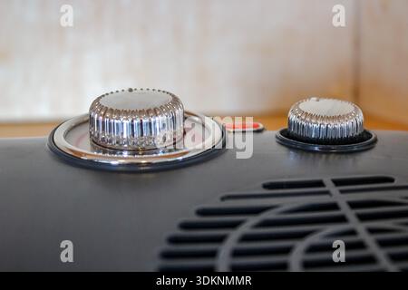 Close-up view of a blue, retro-style electric fan heater sits on a wooden surface with chrome details and two control knobs. Stock Photo