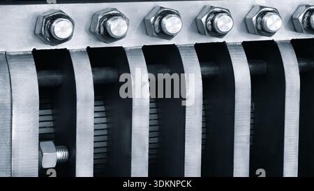 Close-up Industrial metal background, metal radiator with mounting plates tubes and bolts with nuts as part of big industrial machine or conveyor, ind Stock Photo