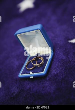 Two gold shining wedding rings in open box on a dark background. vertical orientation Stock Photo