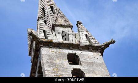 A detailed view of a historic church tower with an intricately carved stone spire against a bright blue sky. Stock Photo