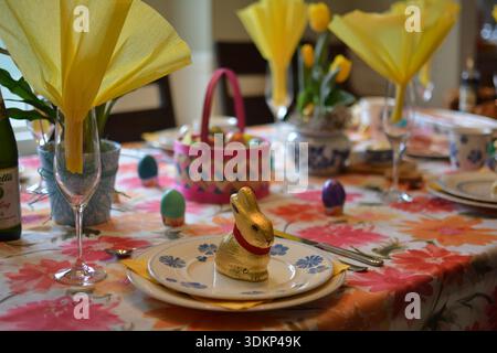 Festive Easter dining table decorated with chocolate bunny, dyed eggs, and yellow napkins for a spring family gathering. Stock Photo