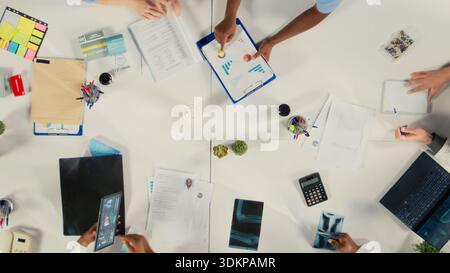 Top down view of experts group reviewing clinical data, working together and sharing their expertise to improve healthcare services at the hospital. Brainstorm treatment ideas. Stock Photo