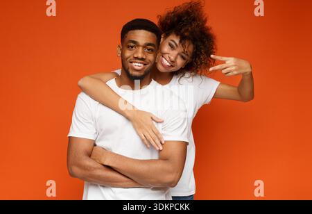 Cheerful couple smiling together, woman gesturing peace sign Stock Photo