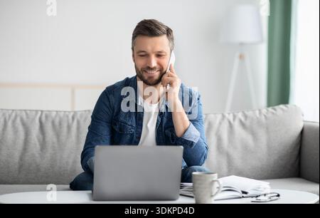 Cheerful man freelancer working from home, using laptop Stock Photo