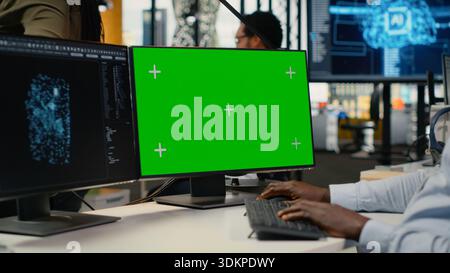 Green screen PC used by technician in office using AI to optimize company systems performance. Worker in startup office uses artificial intelligence tech on mockup computer to automate tasks, camera B Stock Photo