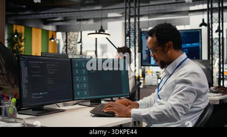 Programmer in office using AI LLM chatbot to get help optimizing systems performance metrics. IT worker in tech agency utilizing generative AI LLM assistant for faster software development, camera A Stock Photo
