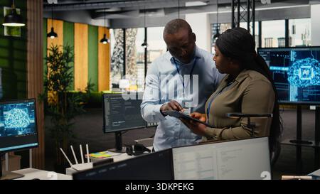 Team of software developers in office automating workflows using artificial intelligence. IT staff members refining deep learning computational models for faster processing, camera A Stock Photo