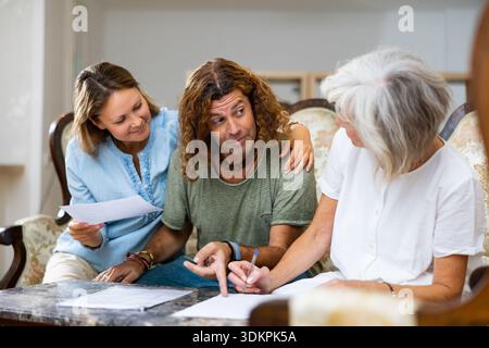 Positive couple and old woman taking notes on the sofa at home Stock Photo
