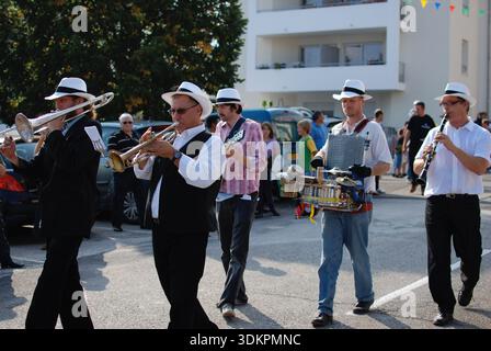 Traditional brass band musicians in white hats performing during a village festival parade in France. Stock Photo