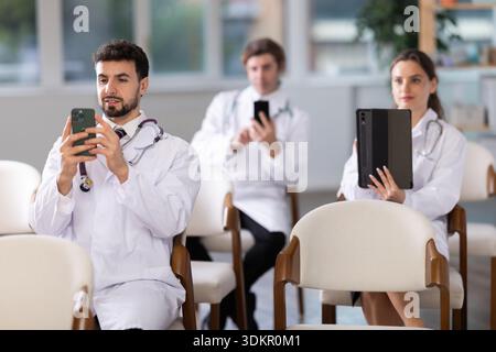 Medical students or doctors using mobile phones to scan QR-code during interactive lesson Stock Photo