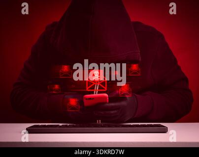 Hacker in dark hoodie using smartphone to send phishing emails on red background, symbolizing cybercrime, email fraud, scamming, identity theft, and c Stock Photo