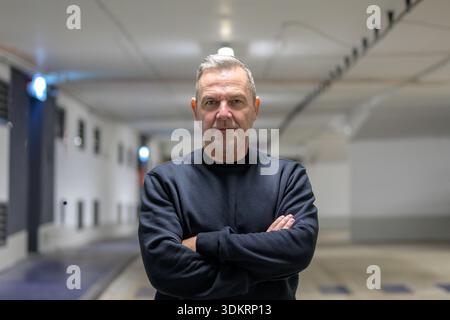 Serious middle-aged businessman standing with crossed arms in a modern underground parking garage, representing professionalism, leadership, business Stock Photo