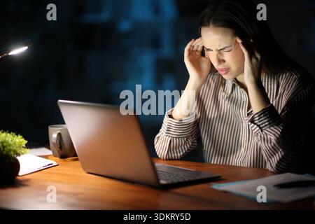 Self employed at home suffering headache working onlne in the night Stock Photo