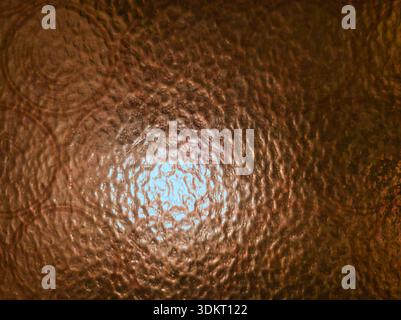 Close up of textured amber glass in Budapest. Features a circular pebbled pattern and warm central light glow. Ideal for vintage interior design Stock Photo