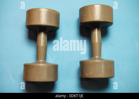 Training dumbbells resting on a light blue yoga mat Stock Photo