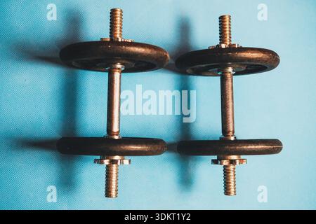 Training dumbbells resting on a light blue yoga mat Stock Photo