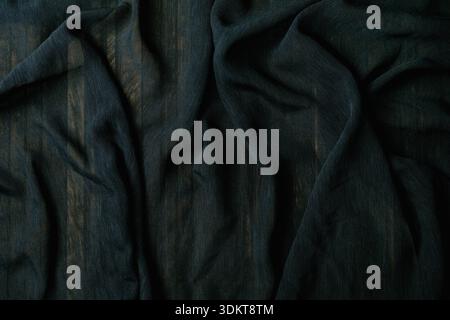 Dark green crumpled fabric with natural wrinkles and folds creating textured surface. Soft cotton or linen material with organic creases and shadows. Stock Photo