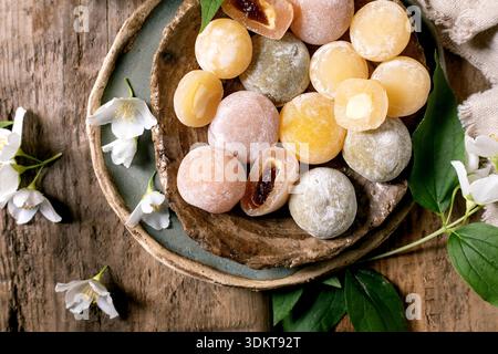 Top view colorful traditional Japanese mochi sweets arranged ceramic bowl wooden background white jasmine flowers decorative elements Stock Photo