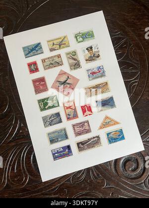 A collection of vintage postage stamps featuring aircraft on a decorative oak table top. Stock Photo