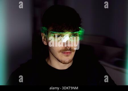 Young man using computer with led cyber glasses Stock Photo
