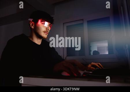 Young man using computer with led cyber glasses Stock Photo