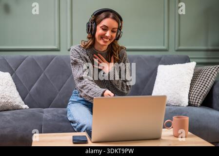 Woman having a joyful conversation on her laptop, sharing laughs and staying connected through the internet from the comfort of her home. Stock Photo