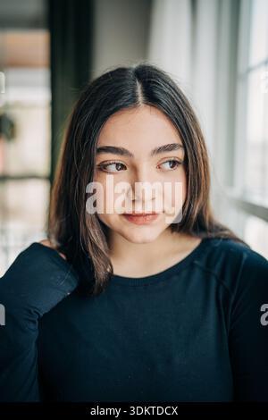 Young woman contemplating, looking away from camera indoors Stock Photo