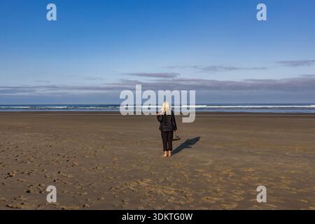 USA, Oregon, Newport, Rear view of woman standing on empty beach Stock Photo