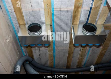 Heat recovery ventilation units mounted on a wooden framework with visible ducts, insulation material, and wooden beams in an unfinished ceiling. Stock Photo