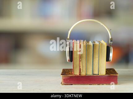 audiobooks concept with  stack of books and headphones on blurry smooth color background Stock Photo