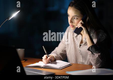 Self employed working in the night scheduling in agenda talking on phone Stock Photo