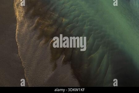 Aerial view of the braided river's turquoise waters meet the dark, volcanic sands in a mesmerizing dance of color and texture, Selfoss, Iceland. Stock Photo
