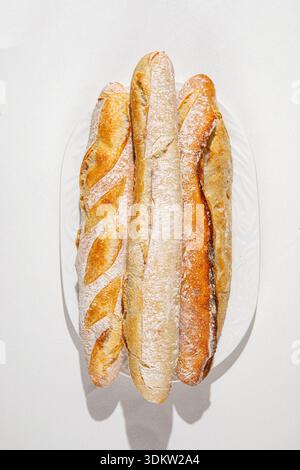Freshly baked assorted baguettes on white plate Stock Photo