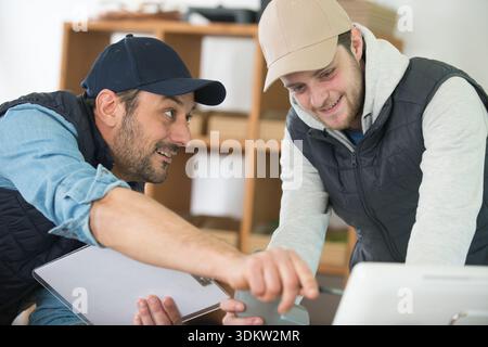 two men in workshop looking at computer screen Stock Photo