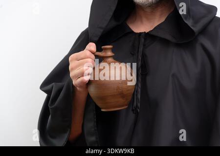 Male monk holding clay jug wearing black robe. Stock Photo